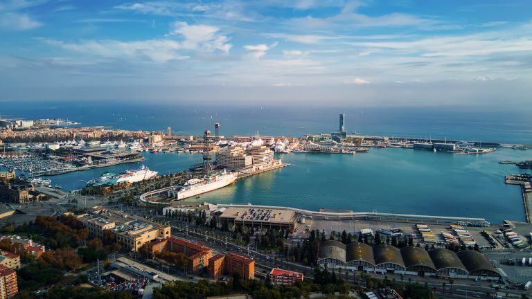 Aerial drone view of Barcelona, Spain. Multiple residential and office buildings, a lot of greenery, Mediterranean sea port